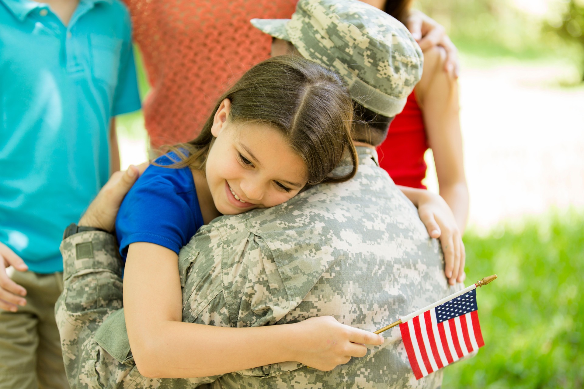 U.S. military veteran welcomed home by family. Children, hugs.