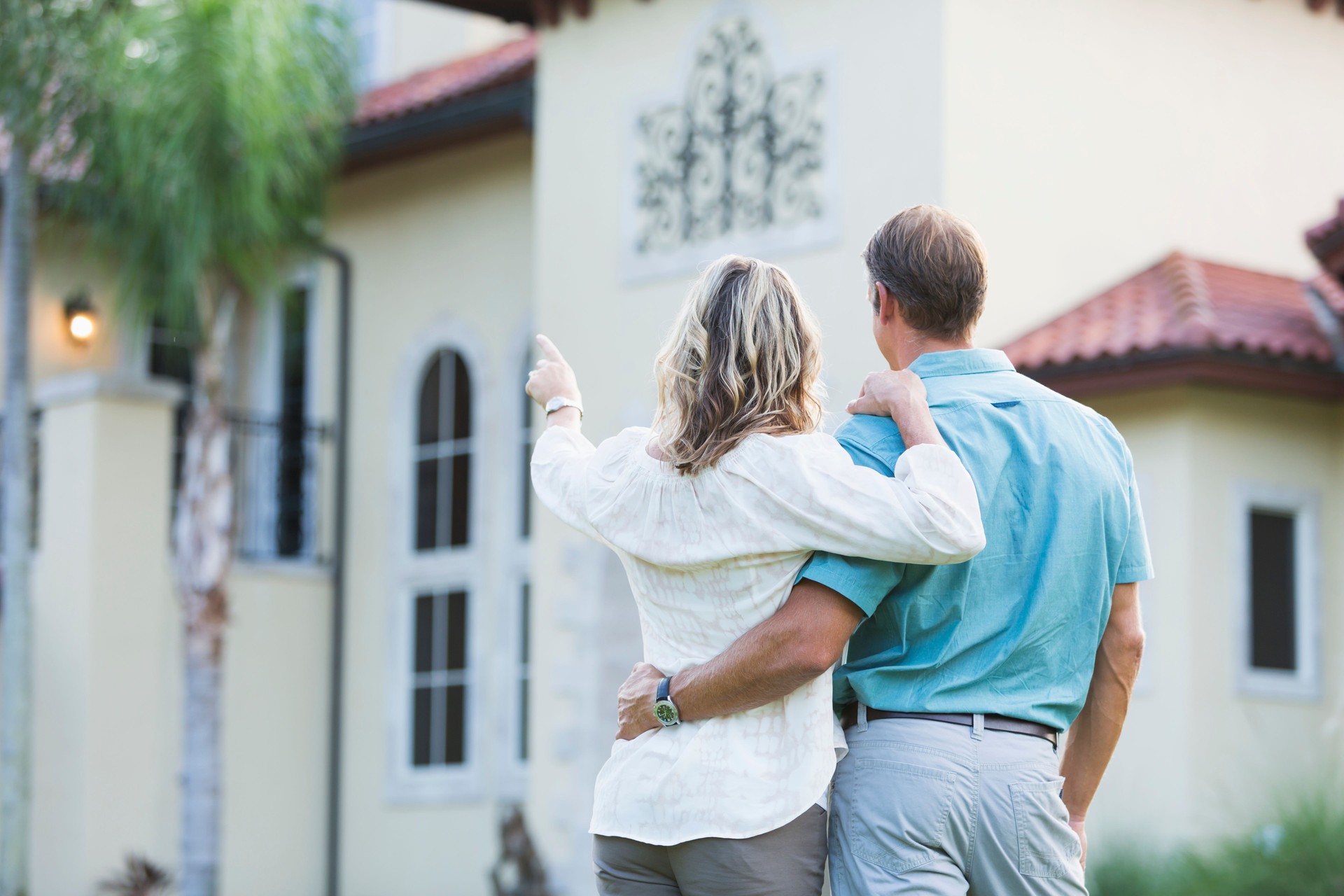 Mature couple standing in front of their mansion