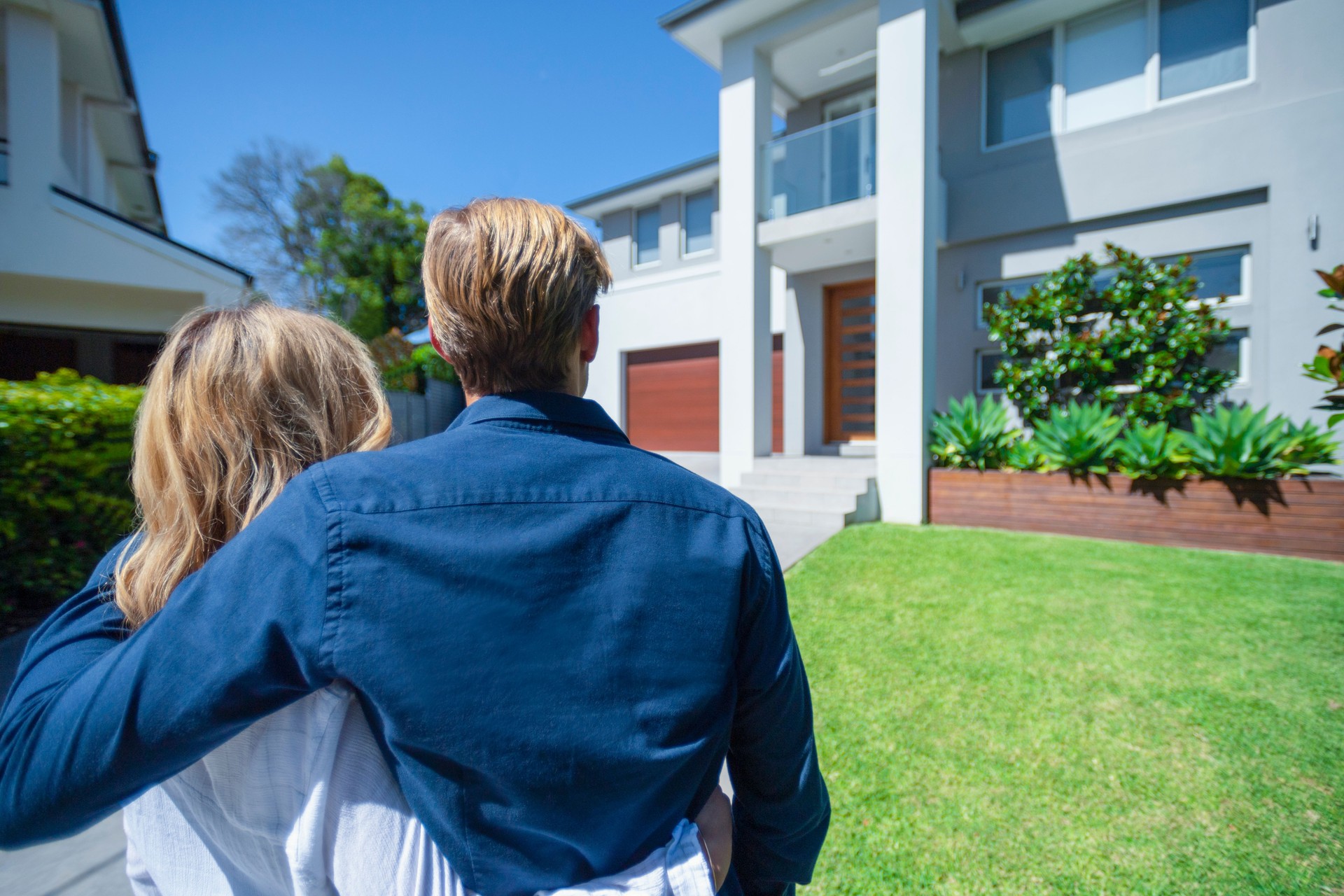 Couple standing in front of their new home.