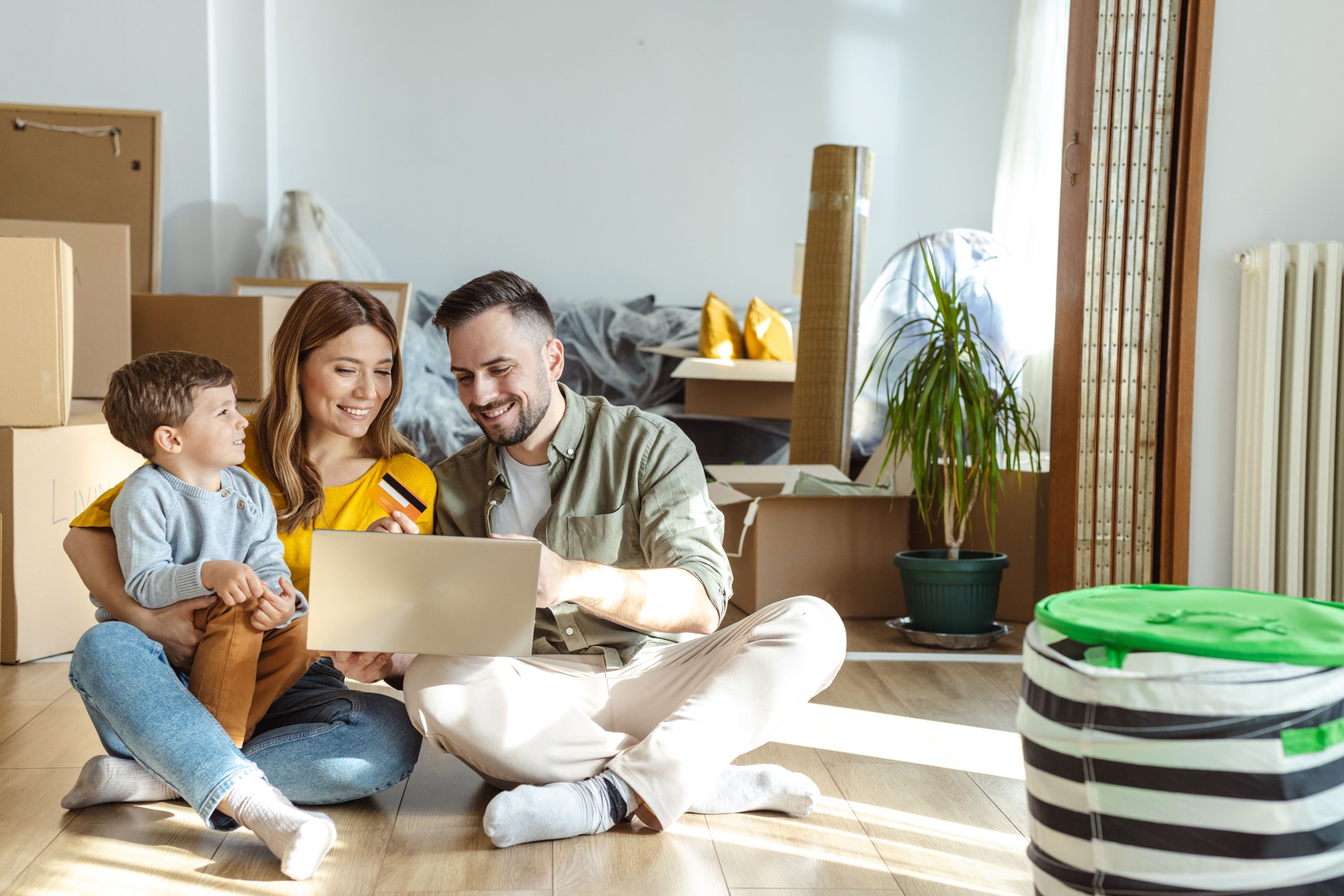 Happy family using laptop and online payment services in new apartment